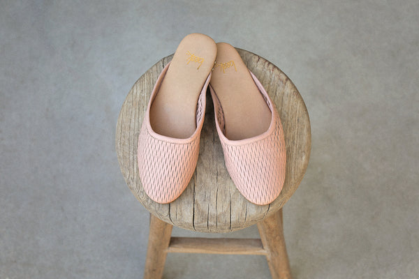 Phoebe Perforated leather ballet mule in blush on a wooden stool