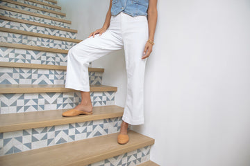 Woman wearing Phoebe Perforated leather ballet mule in honey with white pants and denim vest