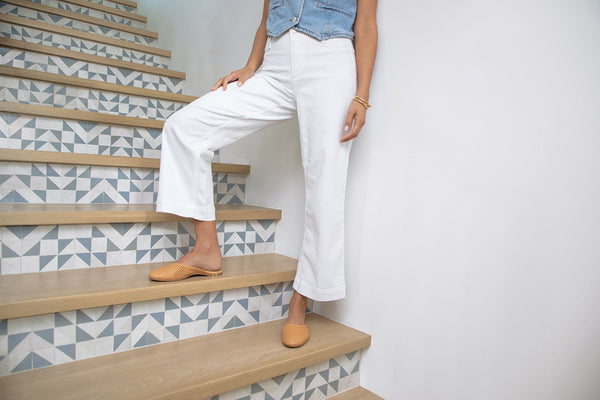 Woman wearing Phoebe Perforated leather ballet mule in honey with white pants and denim vest