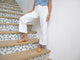 Woman wearing Phoebe Perforated leather ballet mule in honey with white pants and denim vest