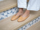 Woman wearing Phoebe Perforated leather ballet mule in honey with white pants