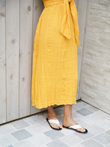 Woman wearing Pip leather flip flop sandal in eggshell/black  with yellow dress