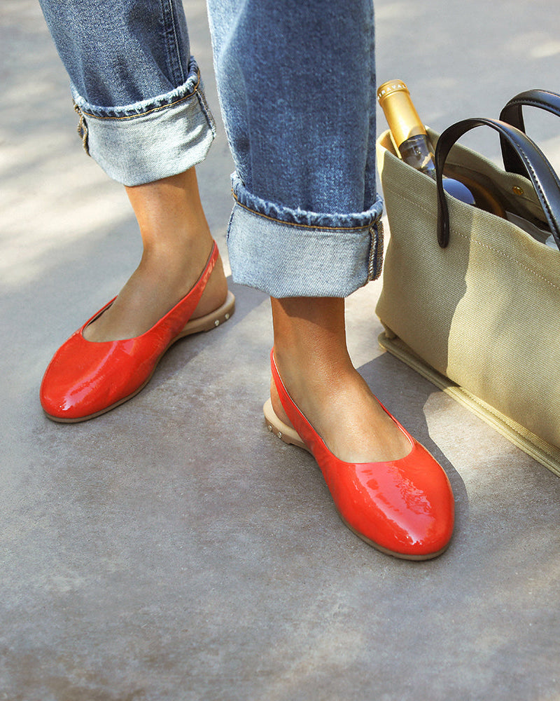 Woman wearing Pipit patent leather ballet mules in tomato