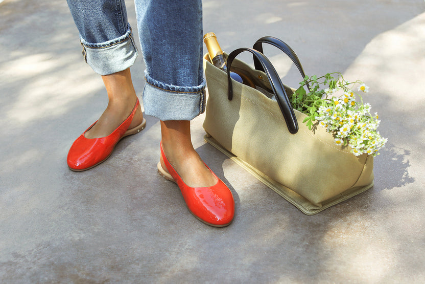 Woman wearing Pipit patent leather ballet mules in tomato