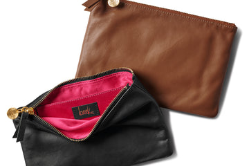 Group shot of leather pouches in black unzipped to show pink lining and beek logo and tan.