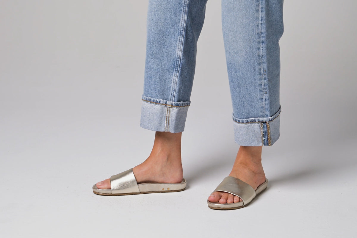 Video of woman walking in Gallito leather slide sandals in platinum wearing jeans