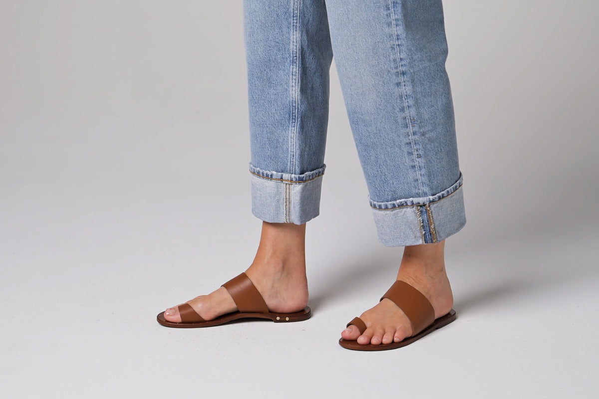 Video of woman walking in Finch leather toe-ring sandals in tan wearing cuffed jeans