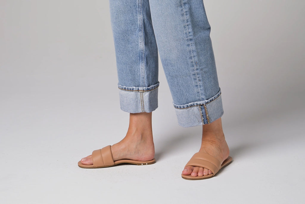 Video of woman walking in Sugarbird leather slide sandals in beach wearing cuffed jeans