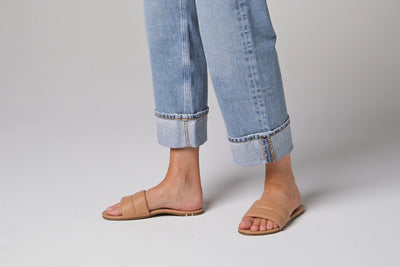 Video of woman walking in Sugarbird leather slide sandals in beach wearing cuffed jeans