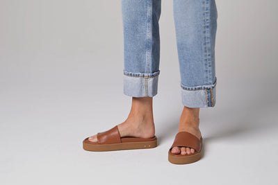 Video of woman walking in Chick leather slide sandals in tan wearing cuffed jeans