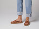 Video of woman walking in Chick leather slide sandals in tan wearing cuffed jeans