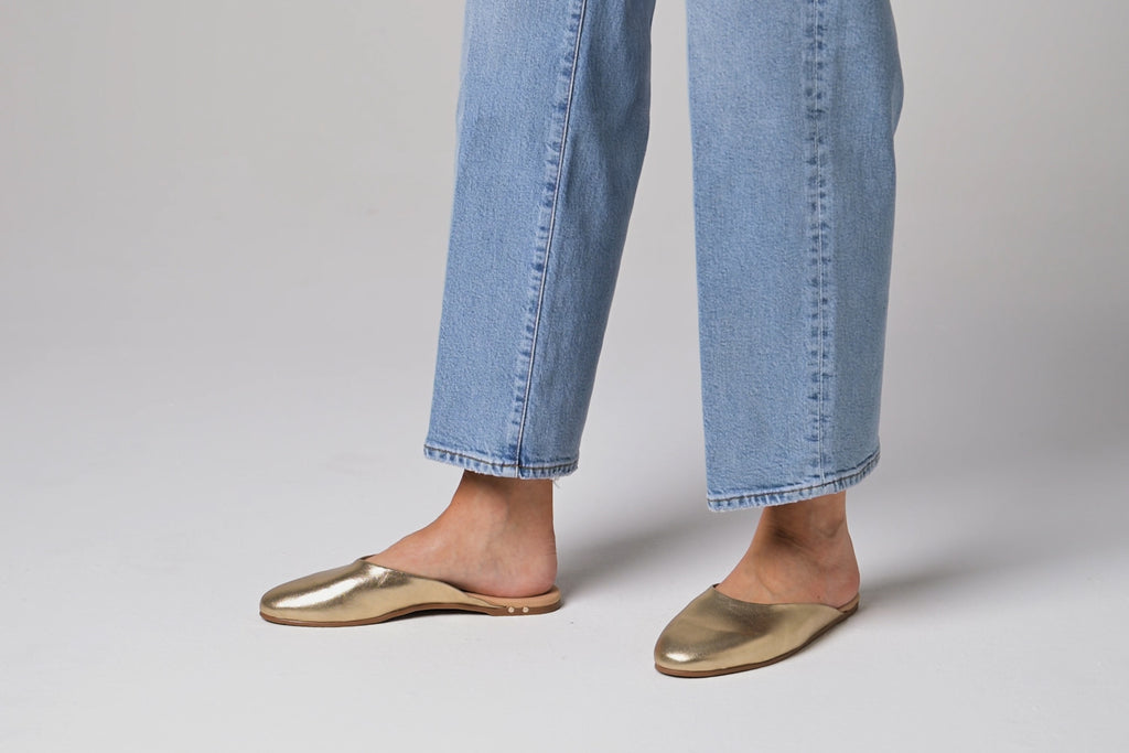 Woman walking in Phoebe leather ballet mules in gold wearing jeans