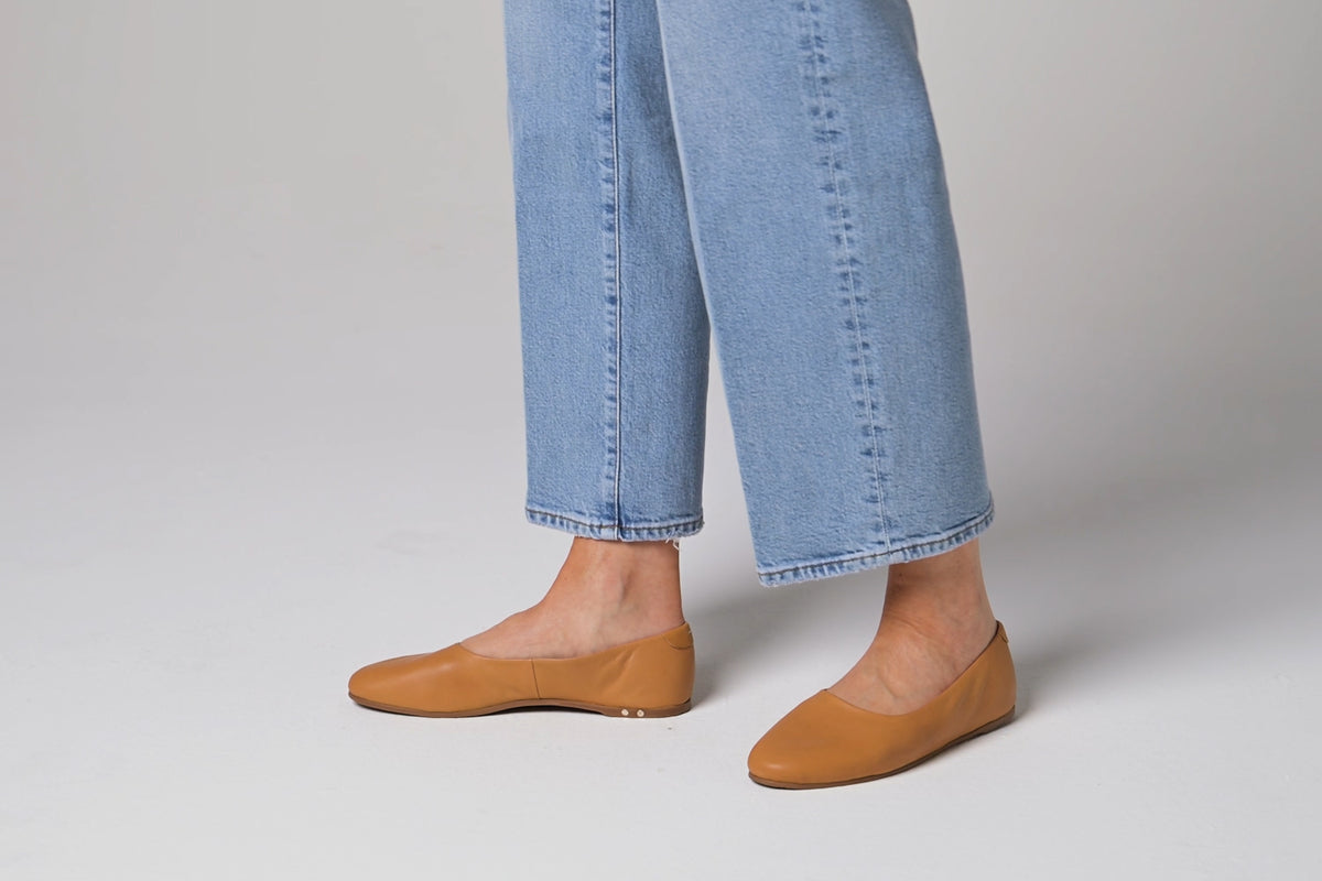 Woman walking in Swiftlet leather ballet slippers in honey with jeans.