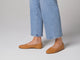 Woman walking in Swiftlet leather ballet slippers in honey with jeans.