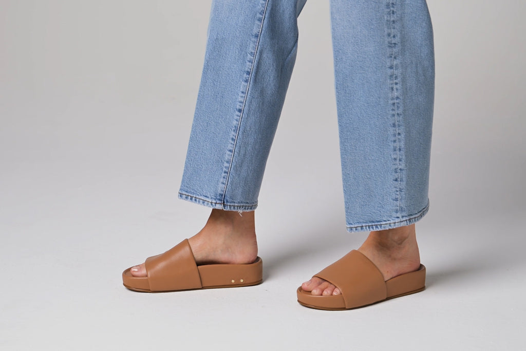 Video of woman walking in Pelican leather slide sandals in honey with jeans