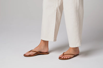 Video of woman walking in Sunbeam leather flip flop sandals in tan with white pants