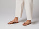 Video of woman walking in Sunbeam leather flip flop sandals in tan with white pants