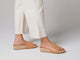 Woman wearing Pelican Jute leather platform sandals in beach with white pants