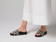 Woman walking in Pelican Woven leather platform sandals in eggshell/black with white dress