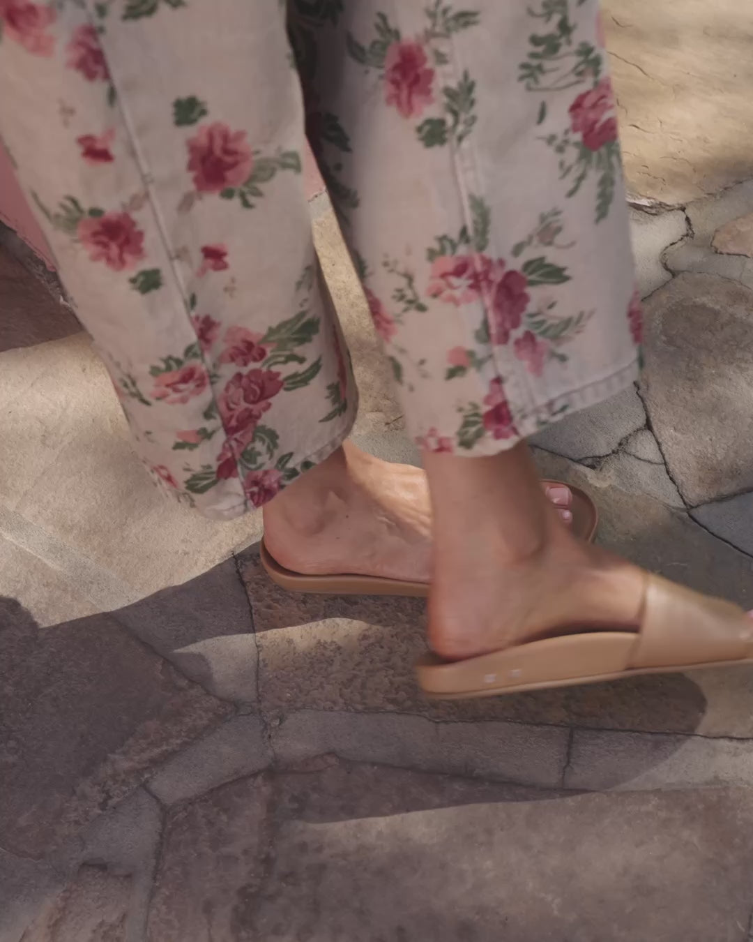 Video of woman wearing Gallito leather slide sandal in honey with floral jeans, walking