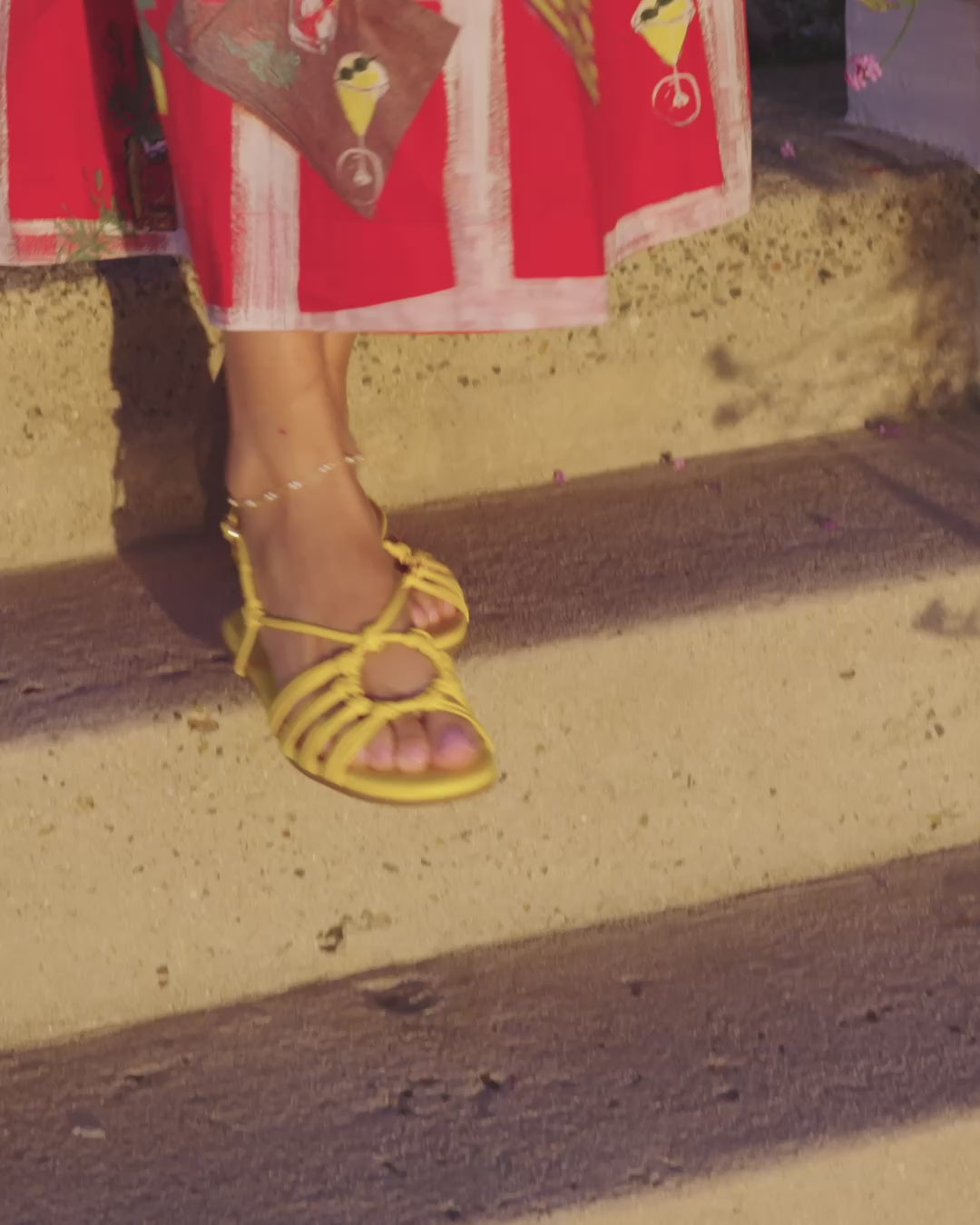 Video of woman wearing Livia leather sandals in lemon with graphic pattern dress, walking