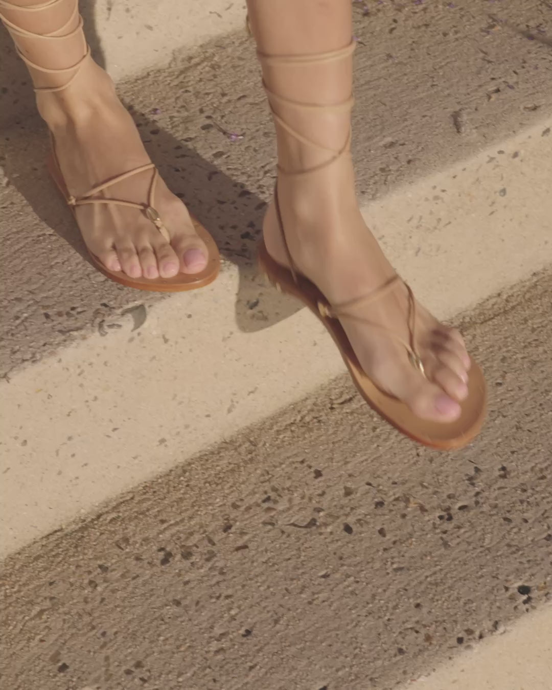 Video of woman wearing Koha leather ankle wrap sandals in beach, walking outside