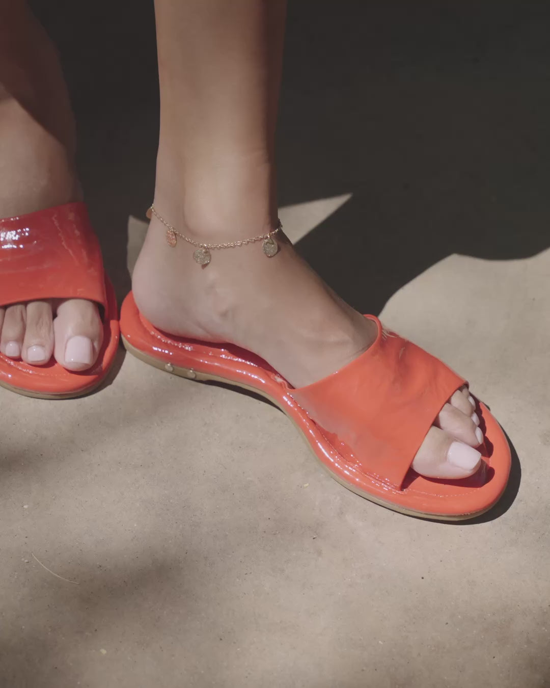 Video of woman wearing Songlark patent leather slides in tomato with anklet, walking
