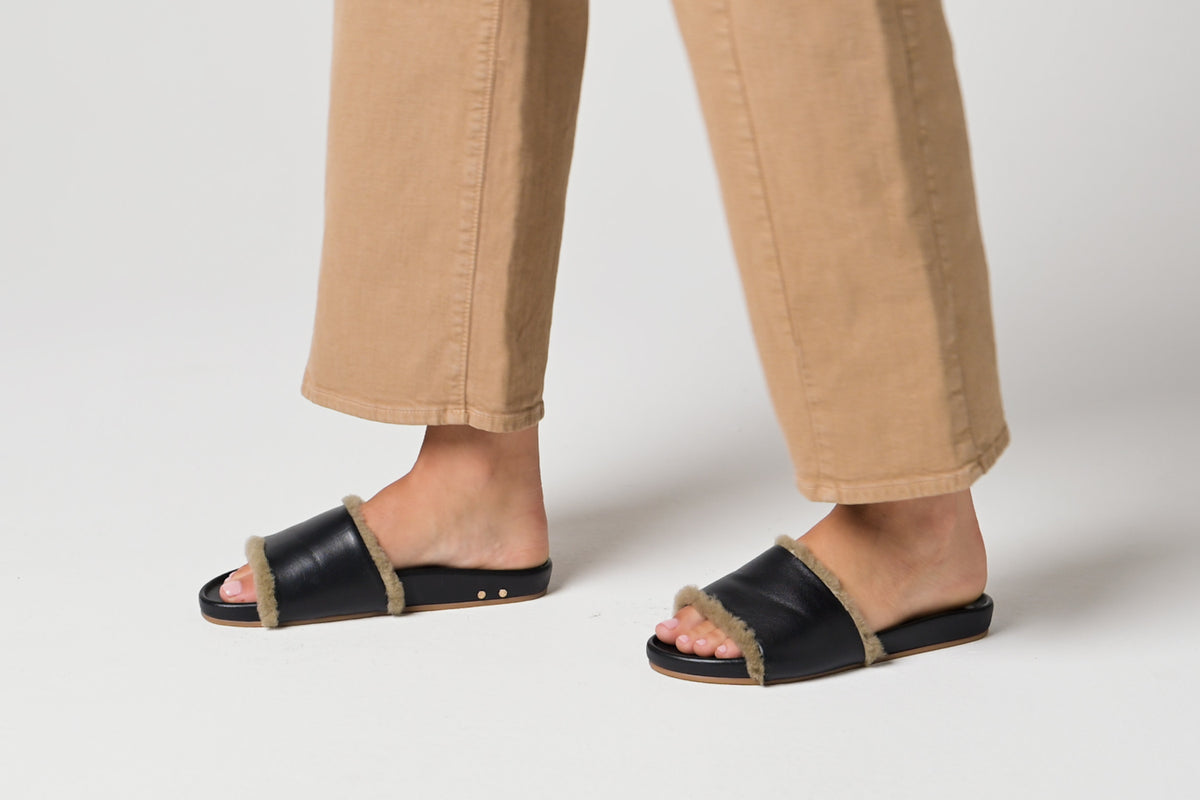 Video of woman walking in Gallito Shearling leather slide sandals in black with tan pants