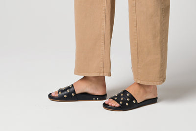 Video of woman walking in Gallito Stud leather slide sandals in black with tan pants