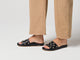 Video of woman walking in Gallito Stud leather slide sandals in black with tan pants
