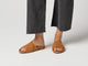 Video of woman walking wearing Kea suede slide sandals in caramel with gray pants.