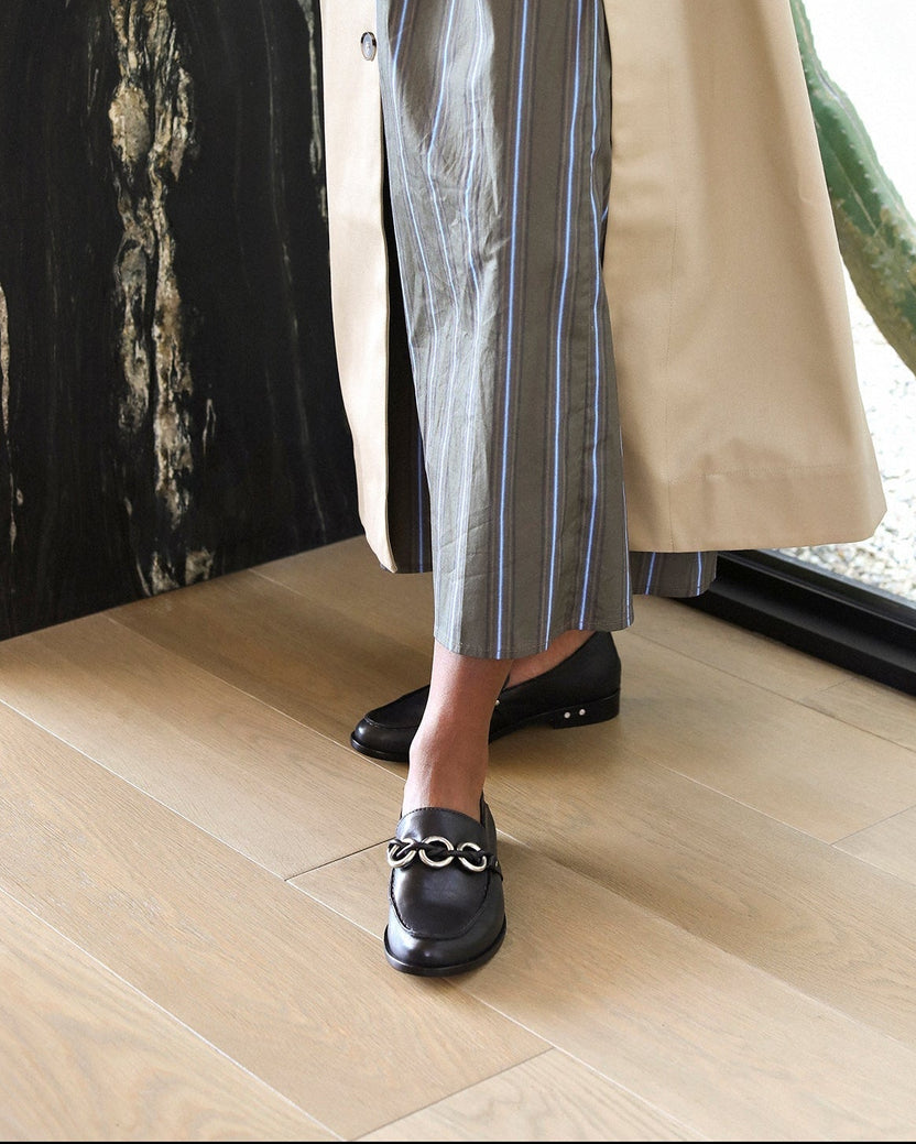 Woman wearing Prion leather loafers in black with striped dress and trench coat