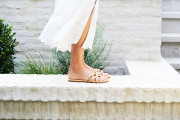 Woman wearing Puffback leather slide sandal in beach with white eyelet dress