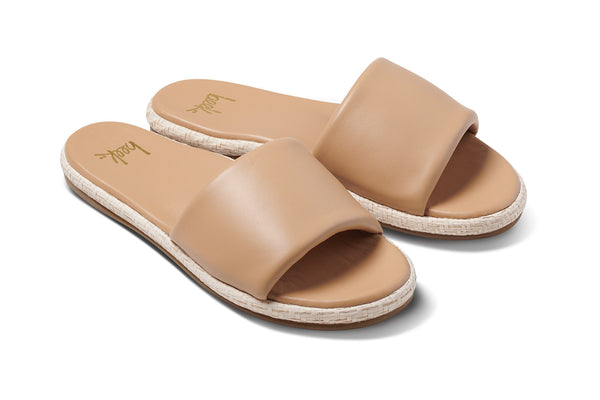 Puffbird Raffia leather slide sandal in beach - angle shot