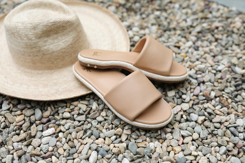 Puffbird Raffia leather slide sandal in beach next to hat