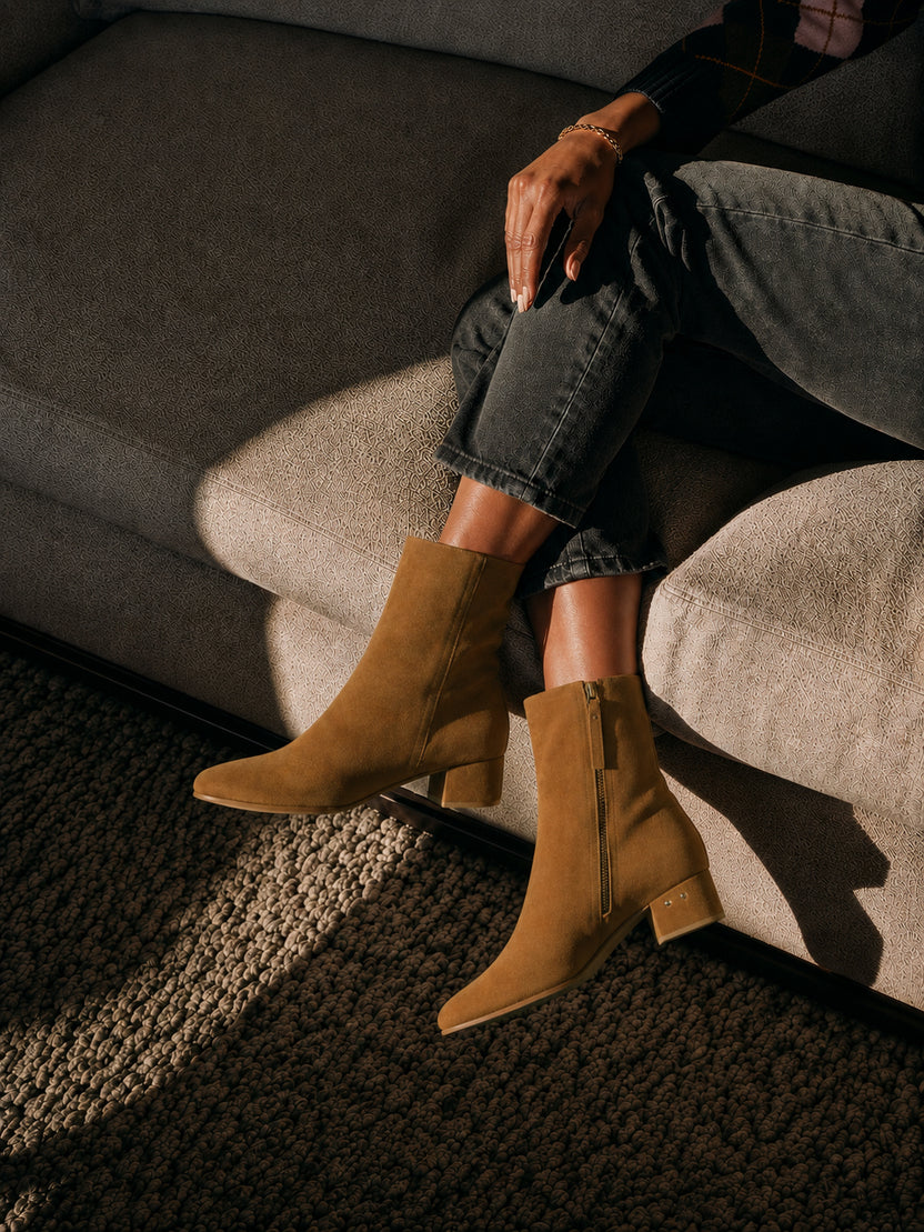 Woman wearing Raven suede boots in toffee with dark jeans sitting on couch