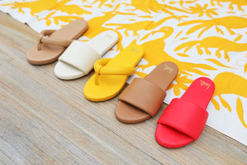 Group shot of Ruby leather thong sandals in beach and sunflower and Baza leather slide sandals in eggshell, honey, cherry.