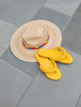 Ruby leather flip flop sandals in sunflower next to hat