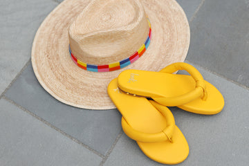 Ruby leather flip flop sandals in sunflower next to hat