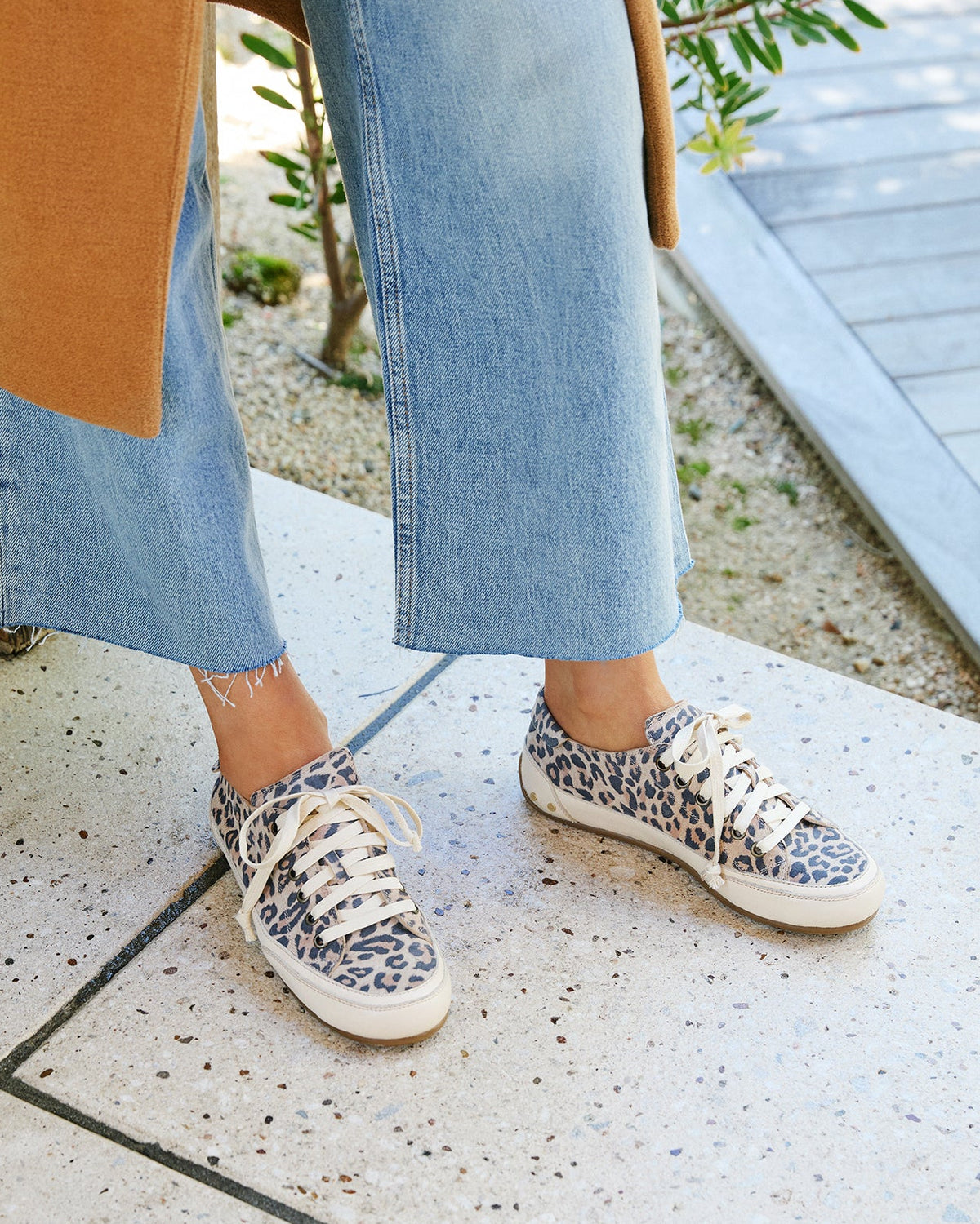 Woman wearing Sandpiper sneakers in leopard  with jeans and coat