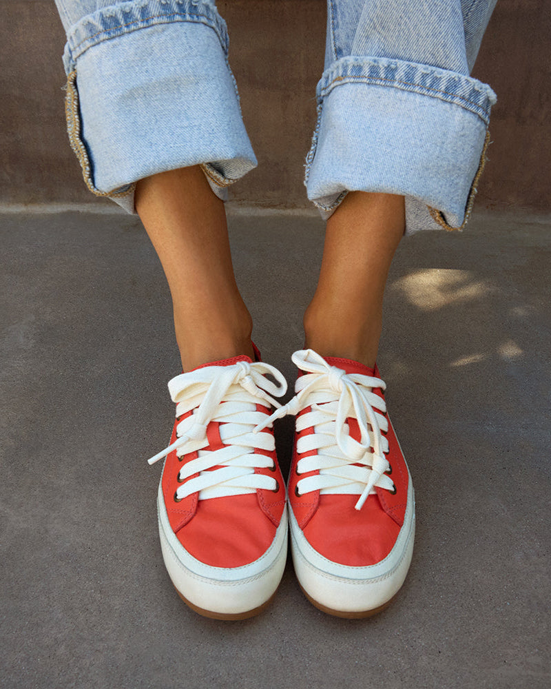 Woman wearing Sandpiper leather sneakers in tomato with jeans