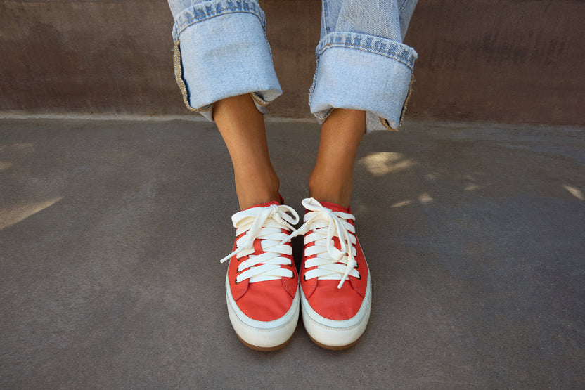 Woman wearing Sandpiper leather sneakers in tomato with jeans