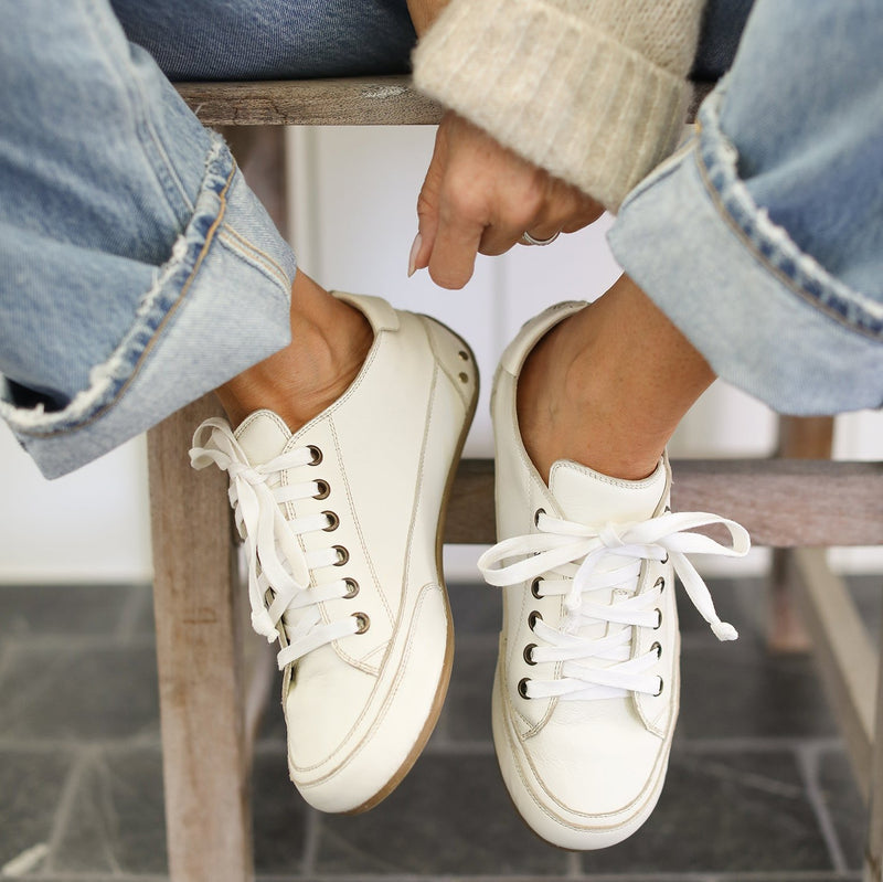 Woman wearing Sandpiper leather sneakers in white with jeans and sweater