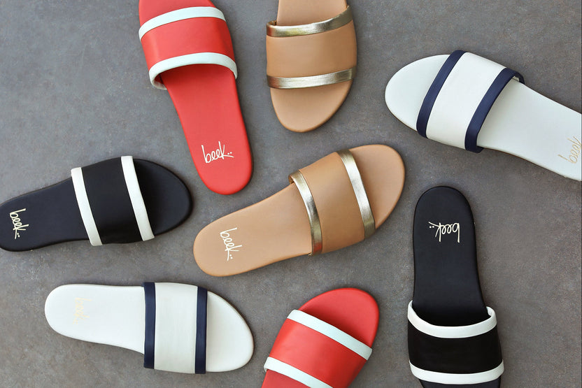 Group shot of Shorebird leather slide sandal in vanilla/navy, black/vanilla, tomato/vanilla, and beach/gold.