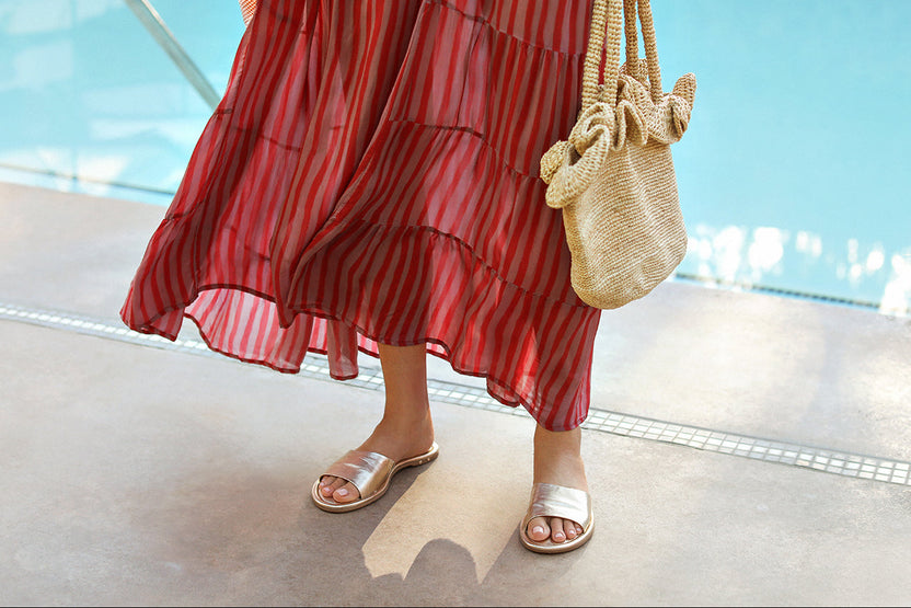 Woman wearing Songlark leather slide sandal in gold with striped dress