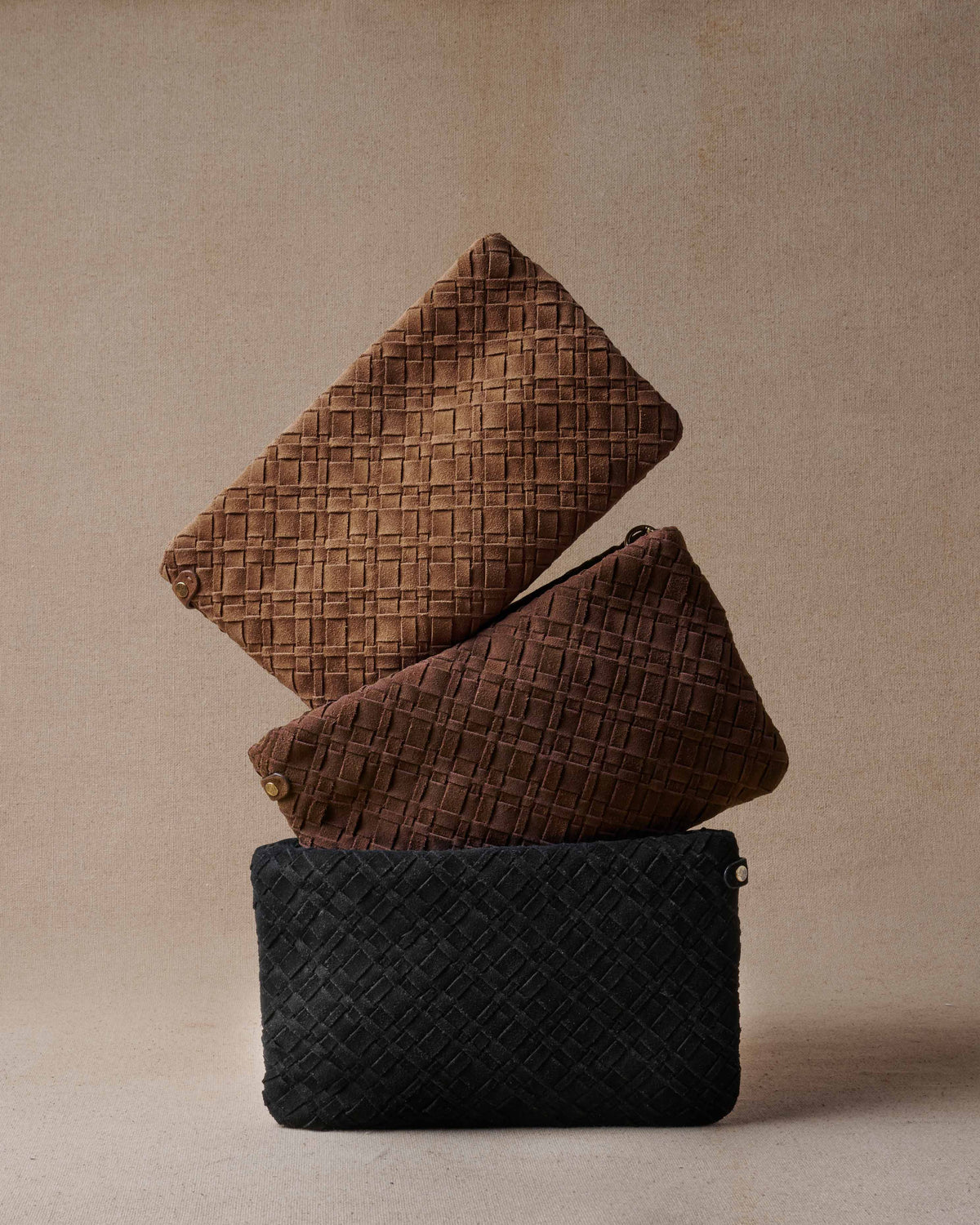 Group shot of Starling suede woven clutch bags in chestnut, coffee, black