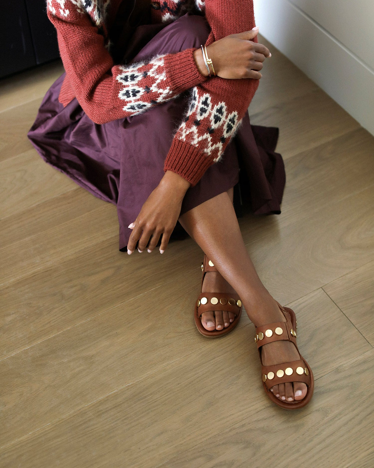 Woman wearing Strix leather back strap sandals in cognac with metallic studs with purple skirt