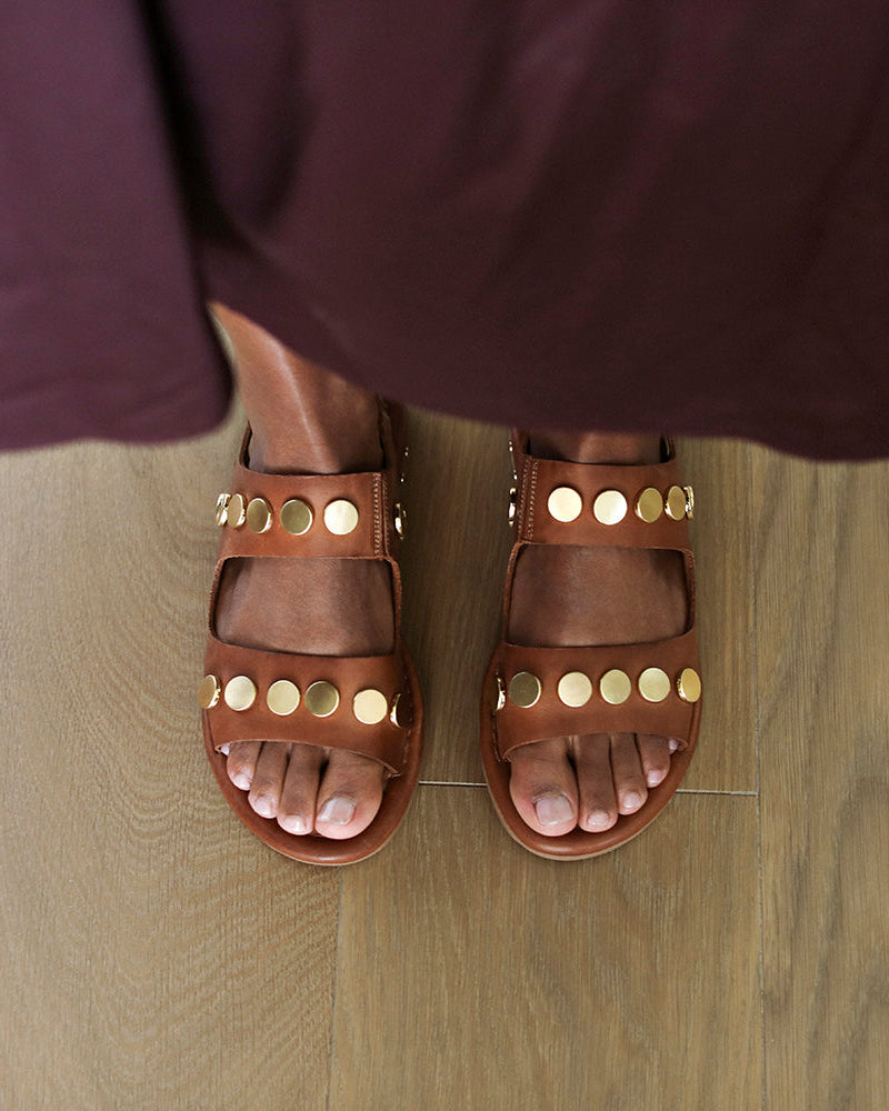 Woman wearing Strix leather back strap sandals in cognac with metallic studs with skirt 