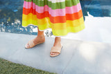 Woman wearing Sugarbird leather slide sandal in beach with colorful striped dress