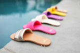 Group shot of Sugarbird leather slide sandals in gold/honey, azalea, eggshell, iris, sunflower, beach colors.